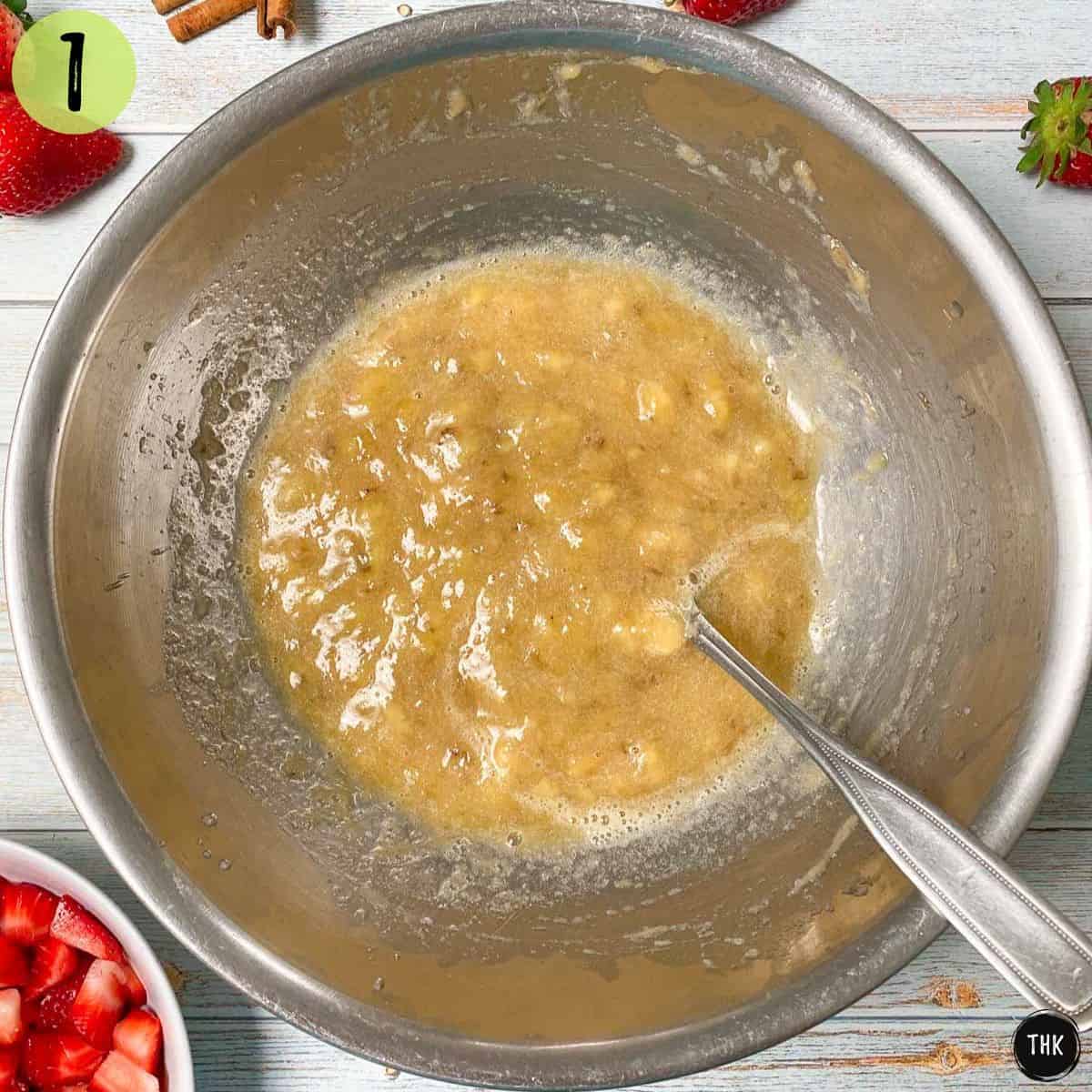 Mashed banana inside large mixing bowl.
