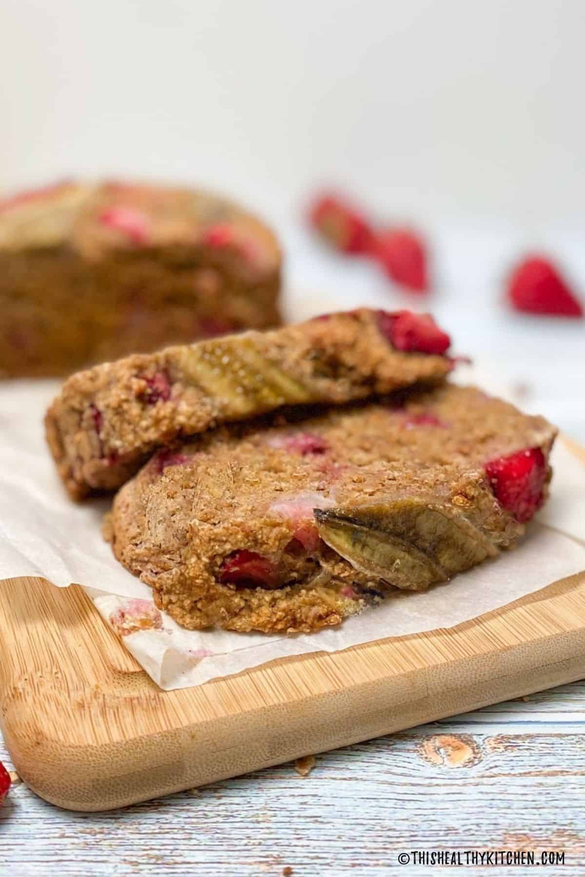 Banana strawberry bread on cutting board with two slices made.