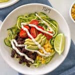 Zucchini noodle bowl with avocado, tomato, black beans and crema fresca on top.