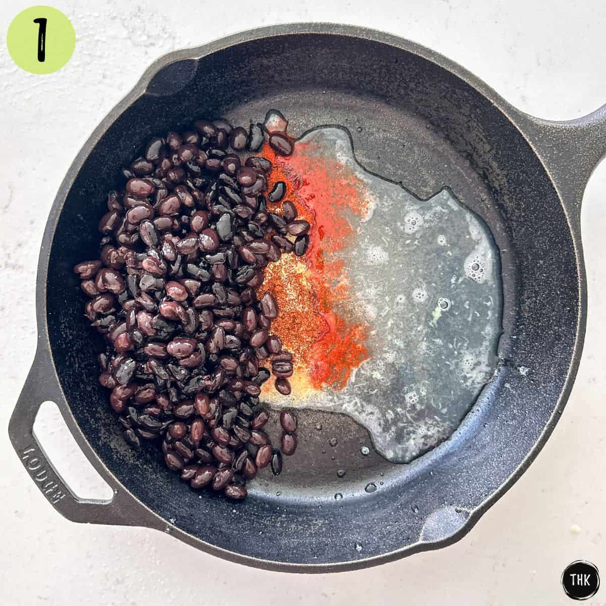 Black beans, spices and lime juice in cast iron pan.