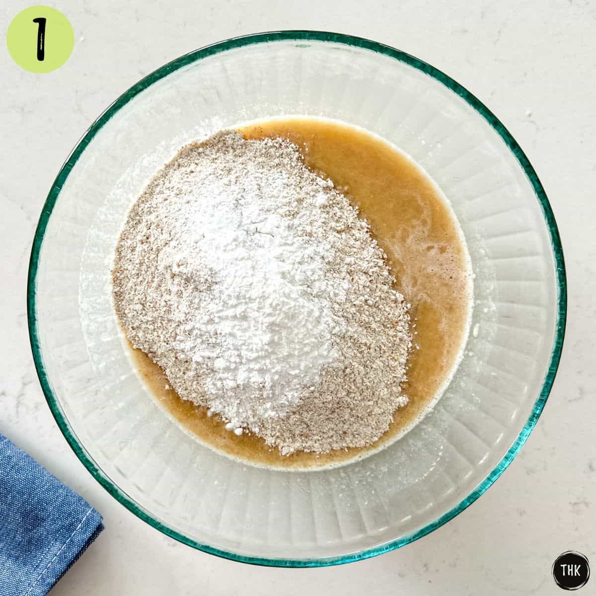 Mashed bananas, vanilla, flour and baking powder inside large mixing bowl.