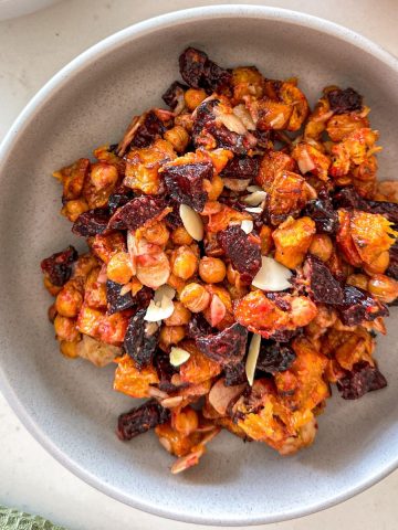 Grey bowl with beet and pumpkin salad with chickpeas, slivered almonds and cranberries.
