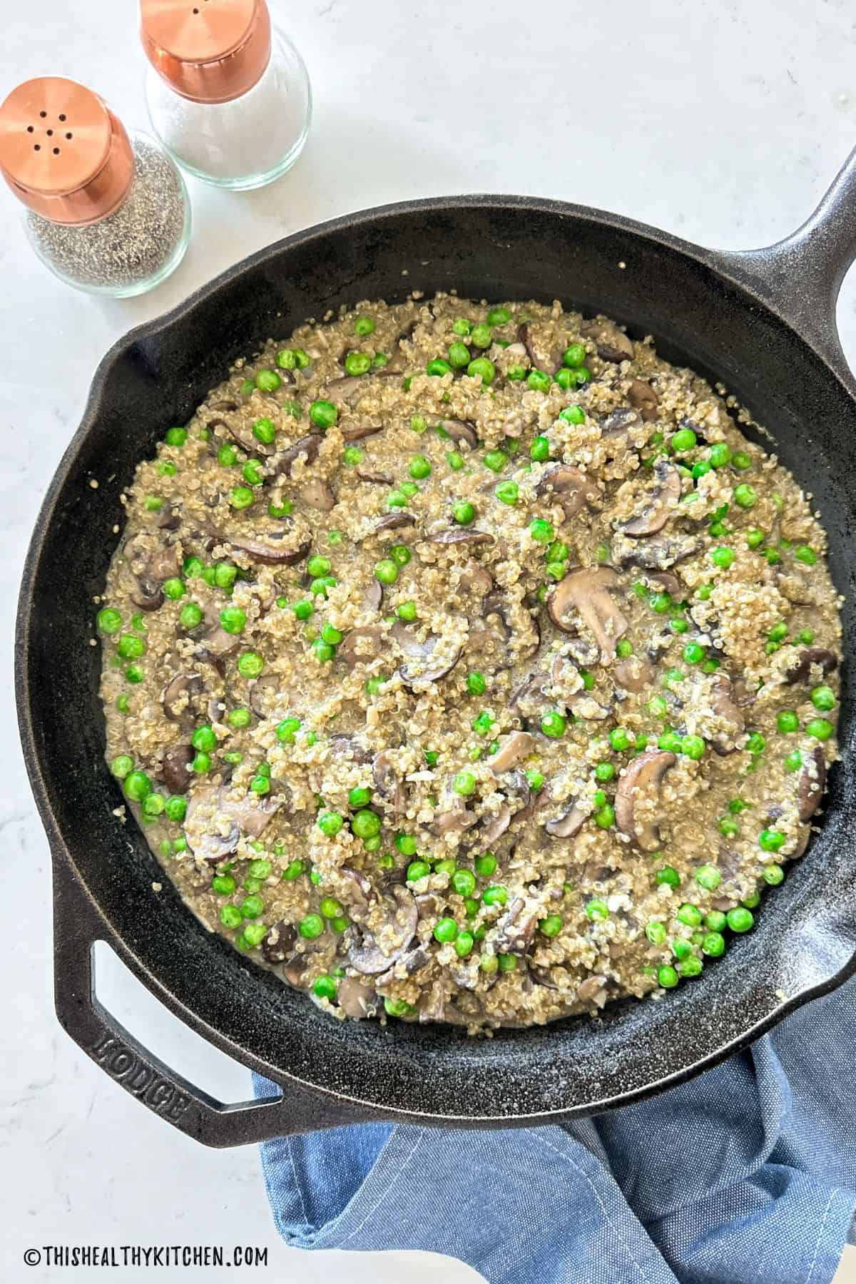 Quinoa risotto with peas and mushrooms in cast iron pan.