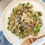 Quinoa risotto with peas and mushrooms with red pepper flakes on top.