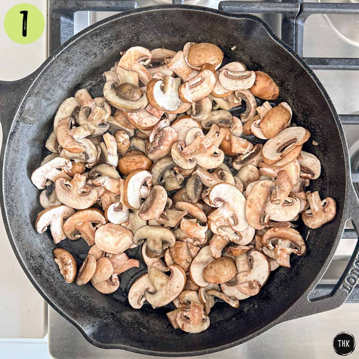 Sliced mushrooms inside cast iron pan.