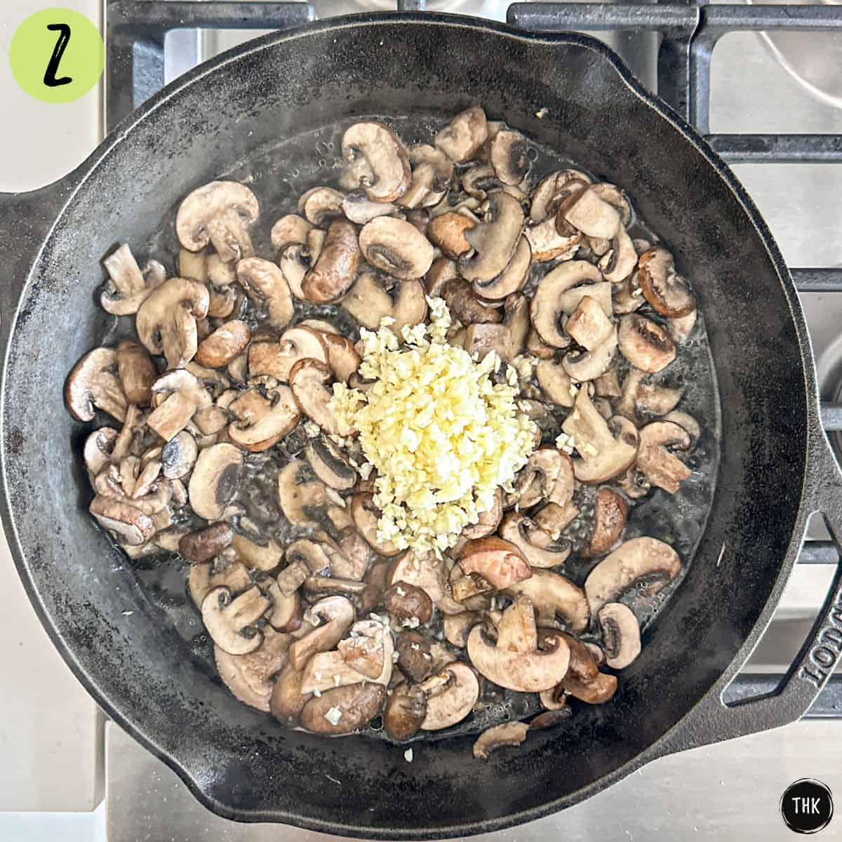Sauteed mushrooms in pan with minced garlic on top.