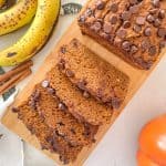 Pumpkin banana bread with chocolate chips on wooden cutting board.