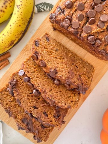 Pumpkin banana bread with chocolate chips on wooden cutting board.