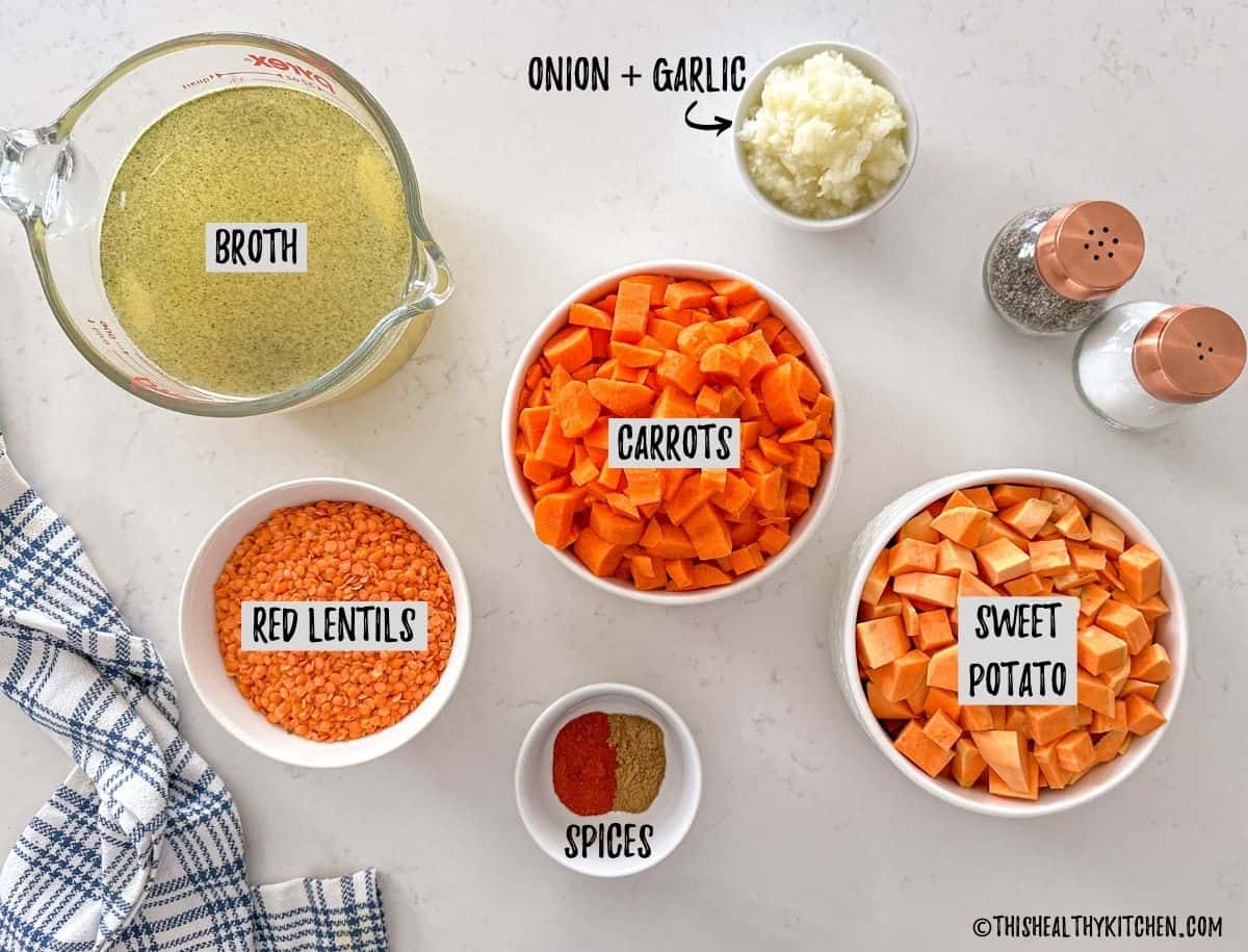 Ingredients needed to make carrot and lentil soup in prep bowls on countertop.