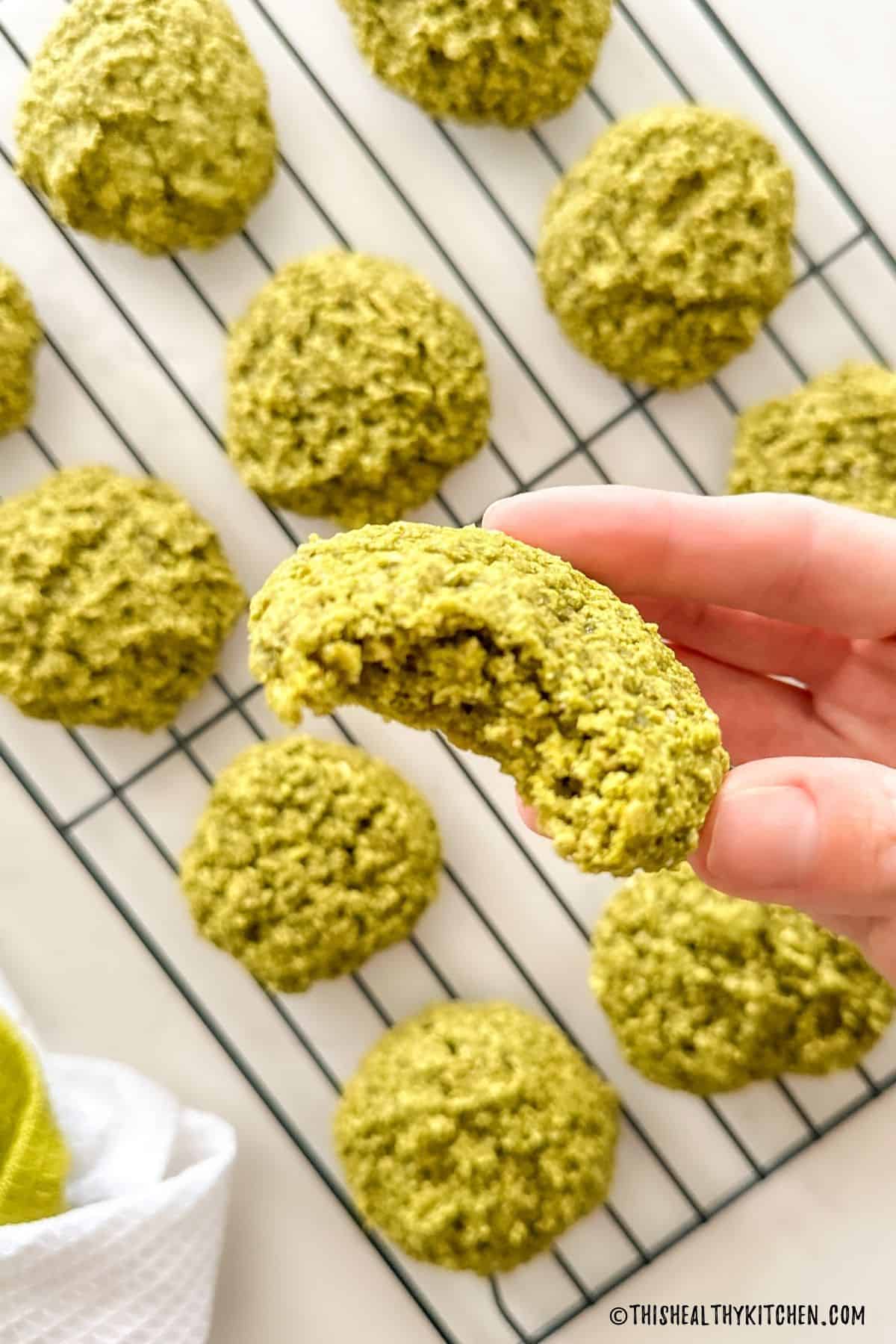 Hand holding up matcha cookie with bite taken out of it.