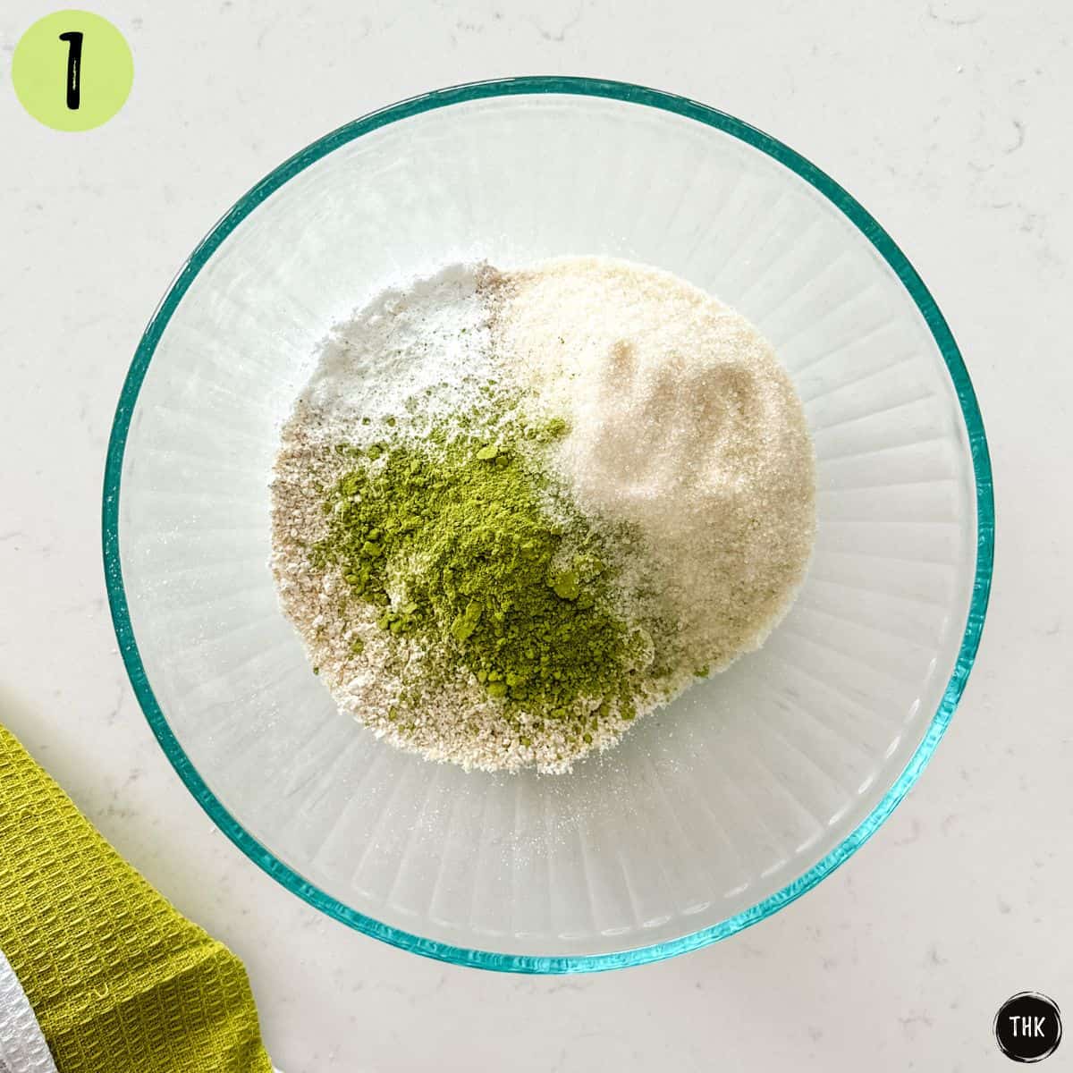 Large mixing bowl with flour, sugar, baking powder and matcha flour inside.