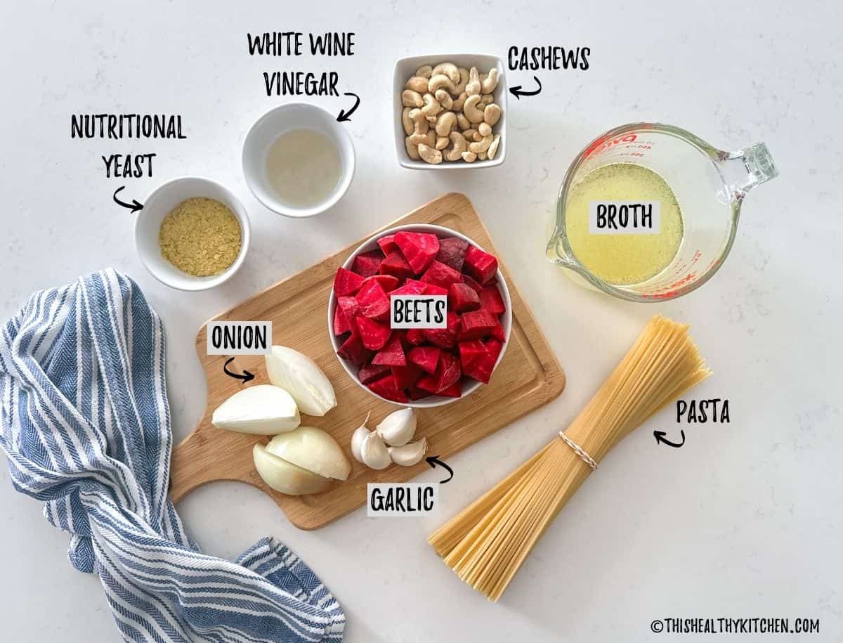 Spaghetti, bowl of beets, onion, garlic, cashews, vinegar, nutritional yeast and broth on kitchen counter.