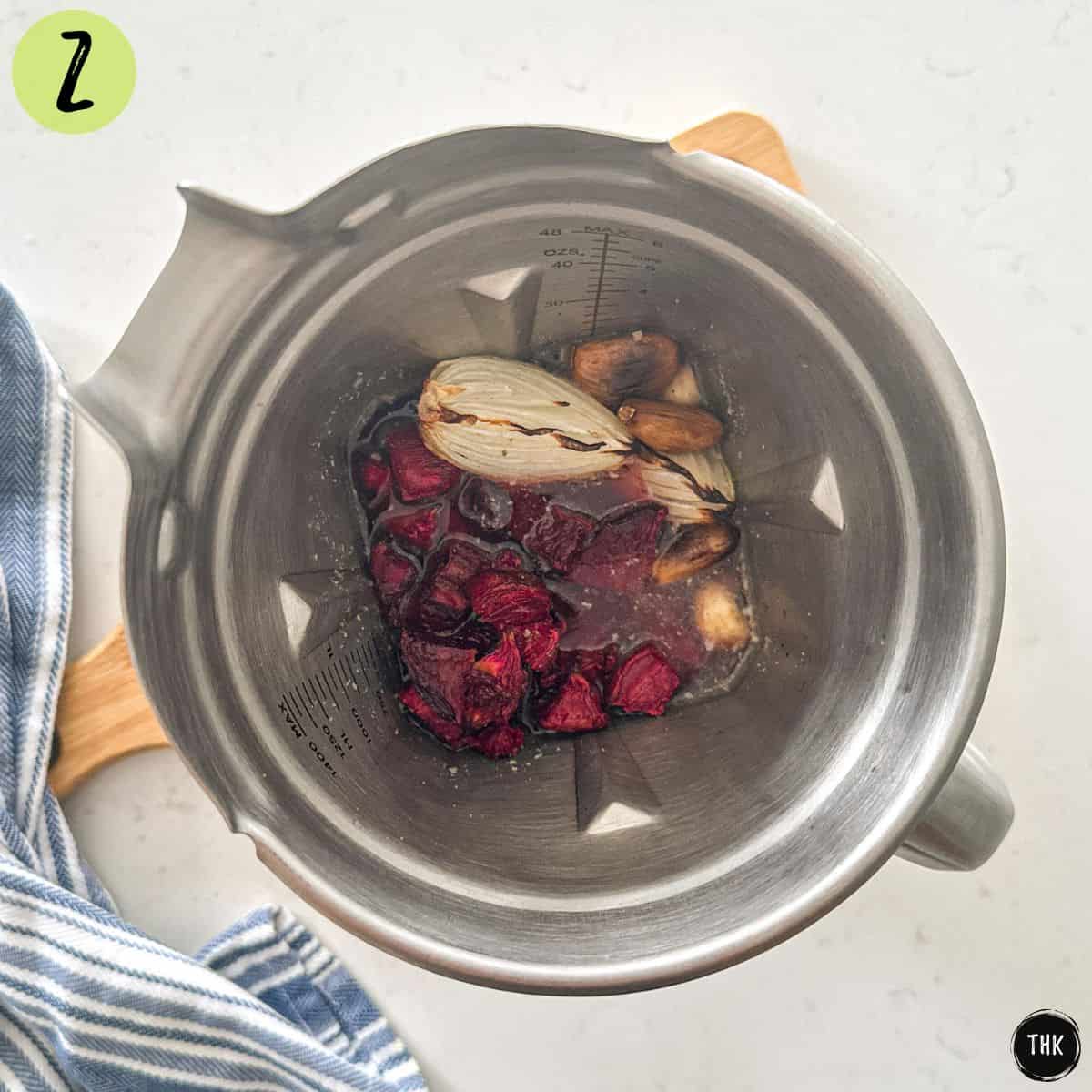 Blender with roasted beets, onion, garlic, broth and seasonings inside.