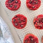 Red beet muffins with chocolate chips on cooling rack.