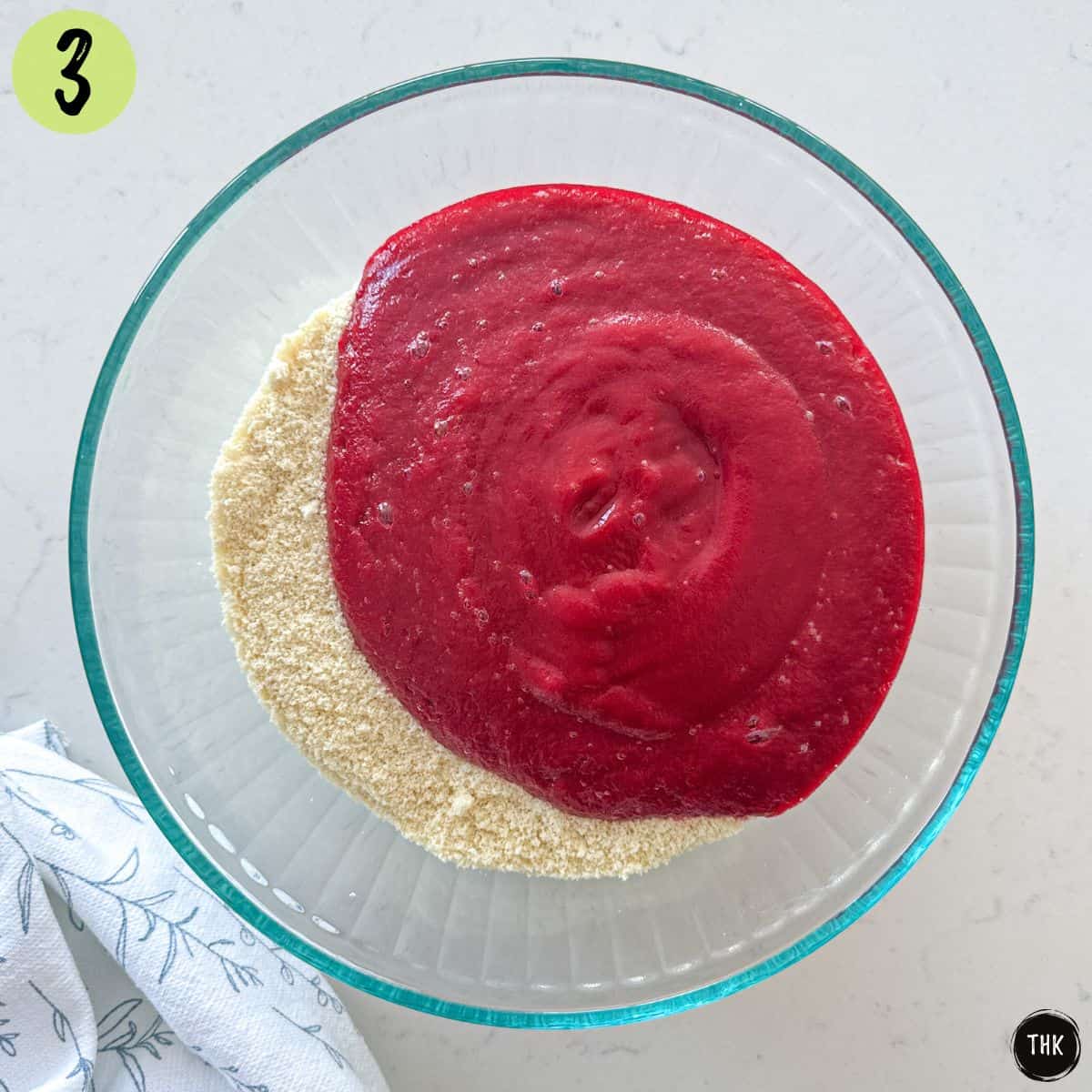 Large bowl of flour mixture with bright pink liquid ingredients on top.