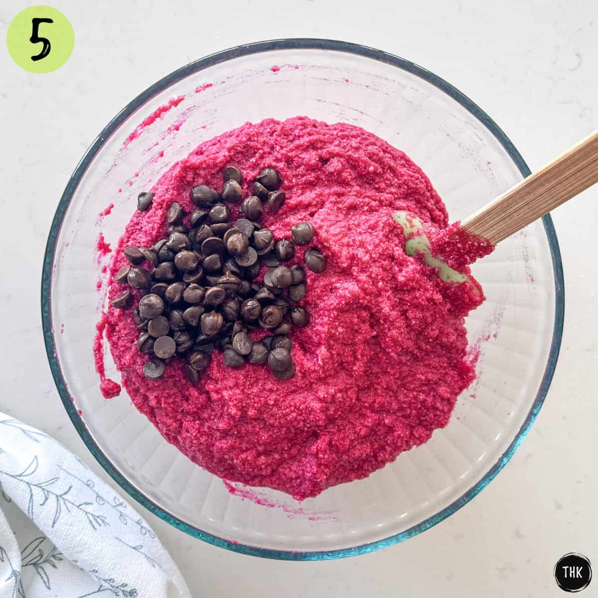 Beet muffin batter in large bowl with chocolate chips on top.