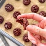 Hand holding a chocolate chickpea cookie with bite taken out.