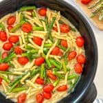 Tomato and asparagus pasta in a light creamy sauce in large black skillet.