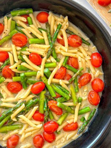 Tomato and asparagus pasta in a light creamy sauce in large black skillet.