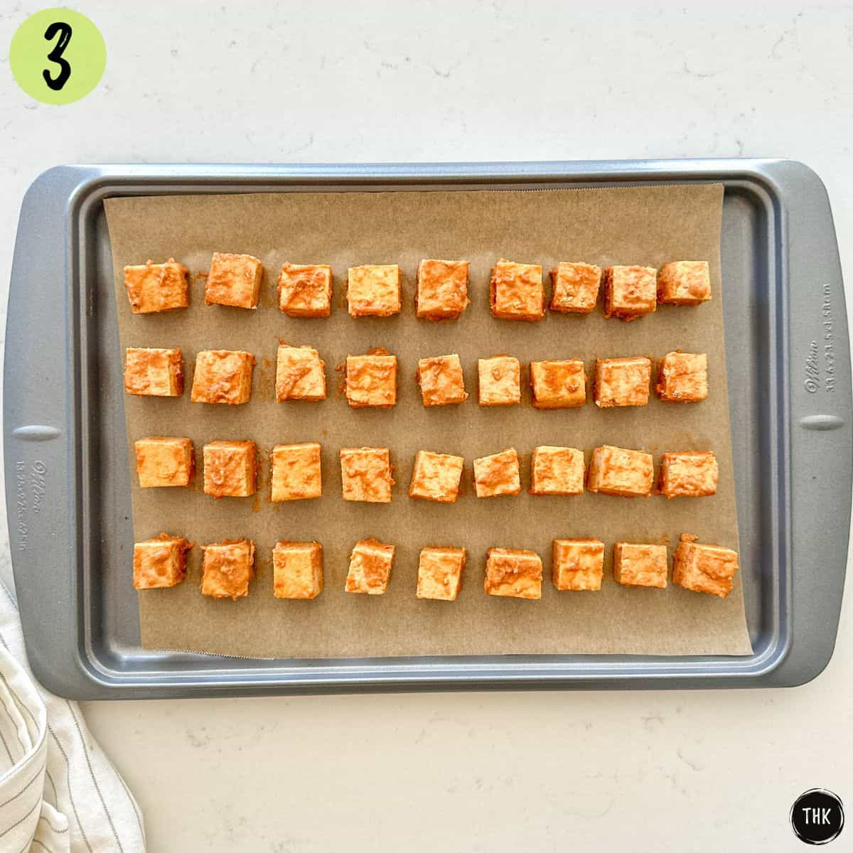 Marinated tofu cubes in a single layer on baking sheet.