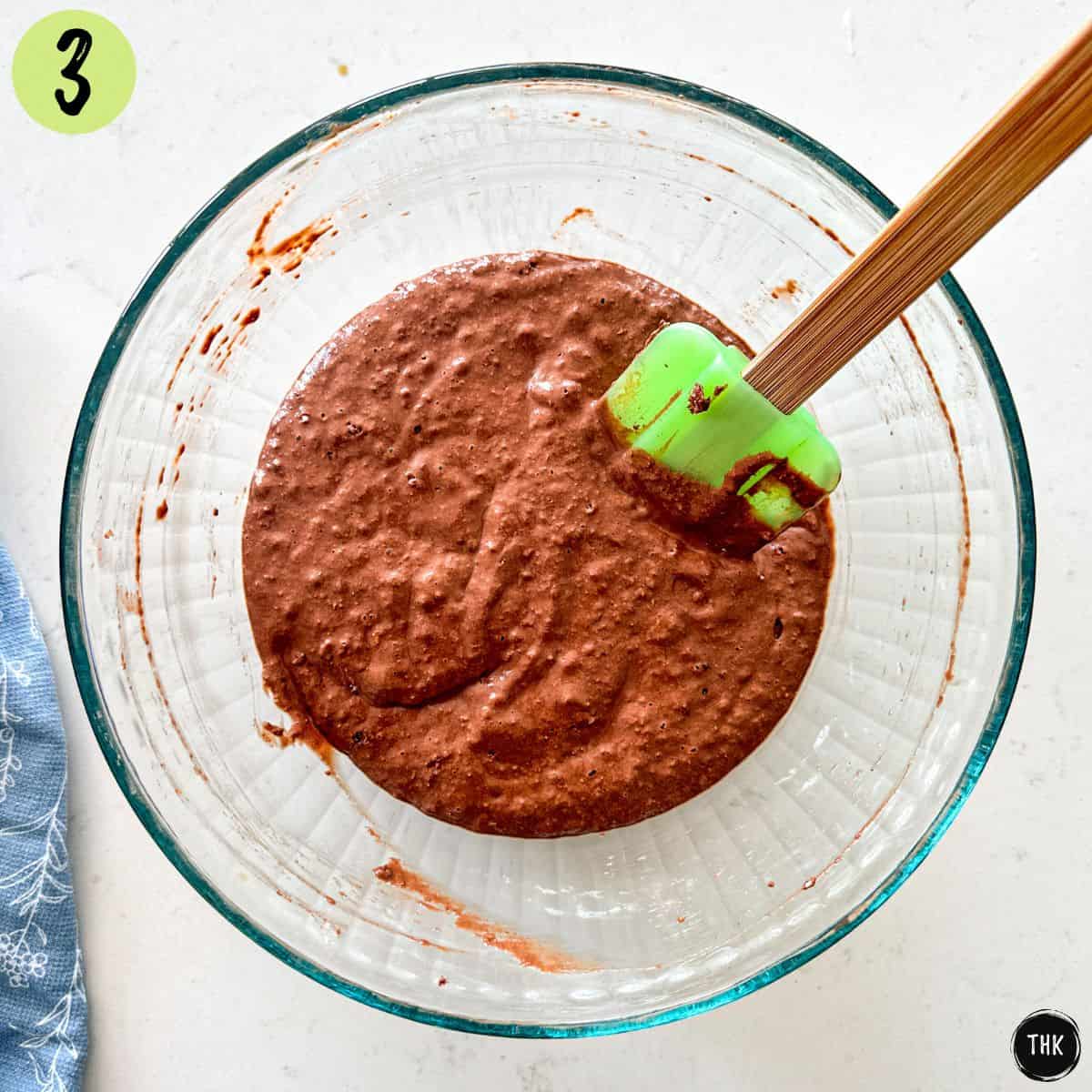 Glass mixing bowl with chocolate waffle batter inside.