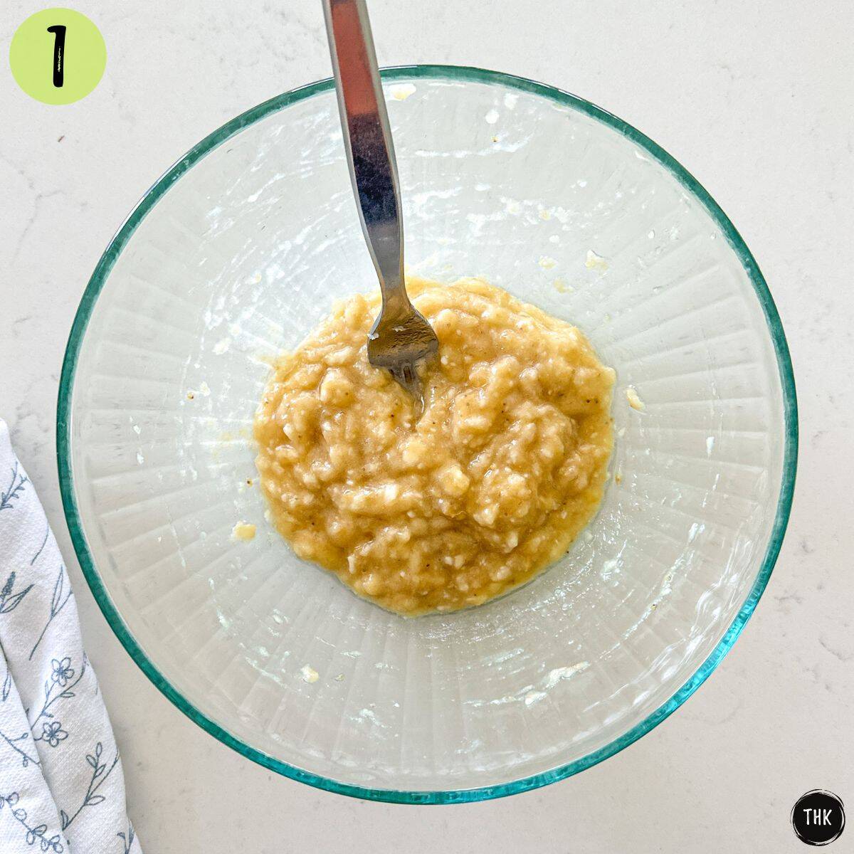Mashed banana in large glass bowl.