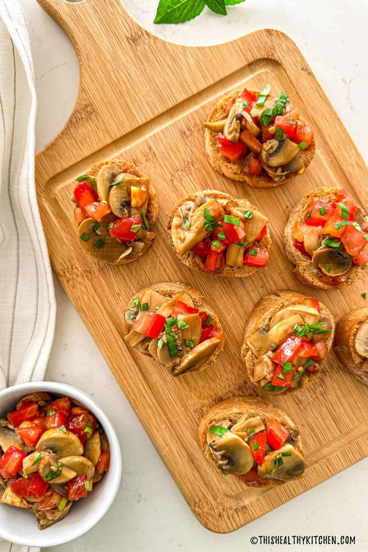 Bruschetta ai funghi on wooden cutting board.