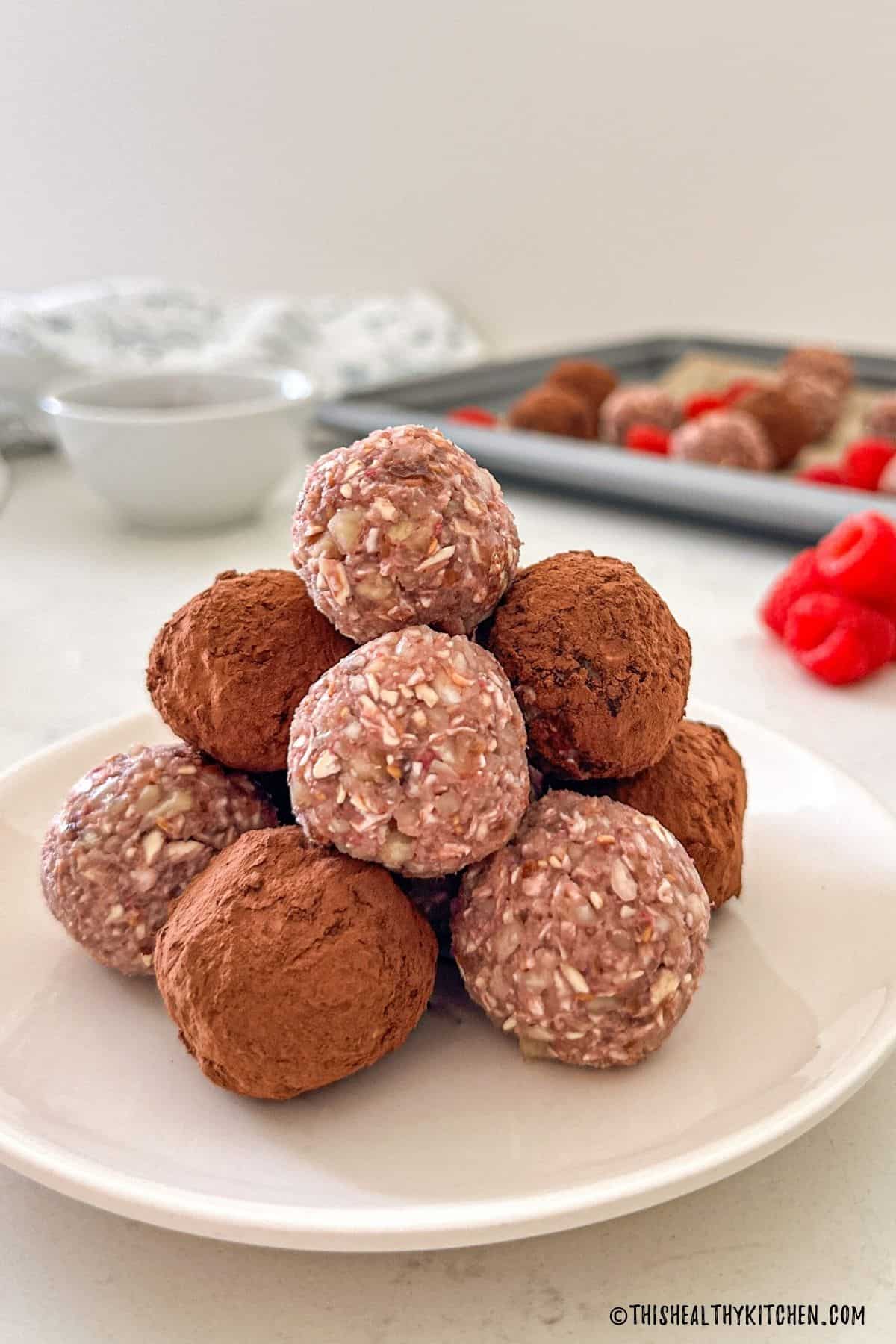Plate with raspberry energy balls stacked on top of one another.