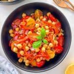 Bowl of salad with roasted red peppers, chickpeas, cherry tomatoes, red onion, and basil.