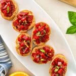 Beet bruschetta on white dish with fresh basil on top.