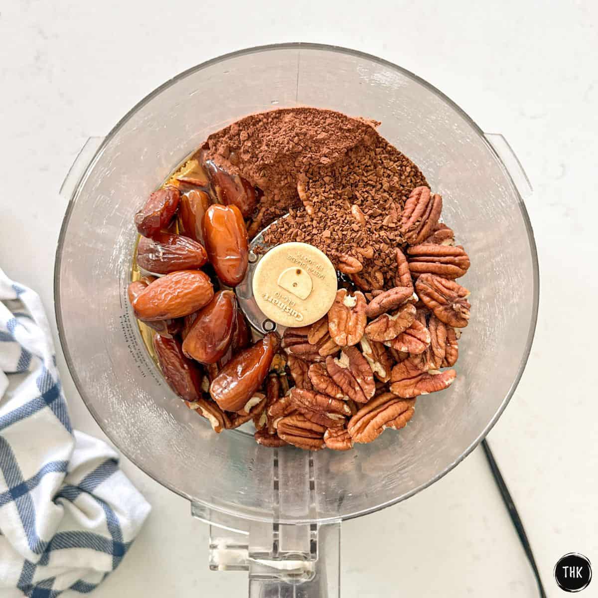 Dates, pecans, cocoa powder, and instant coffee in food processor bowl.