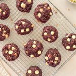 Vegan red velvet cookies with white chocolate chips on cooling rack.