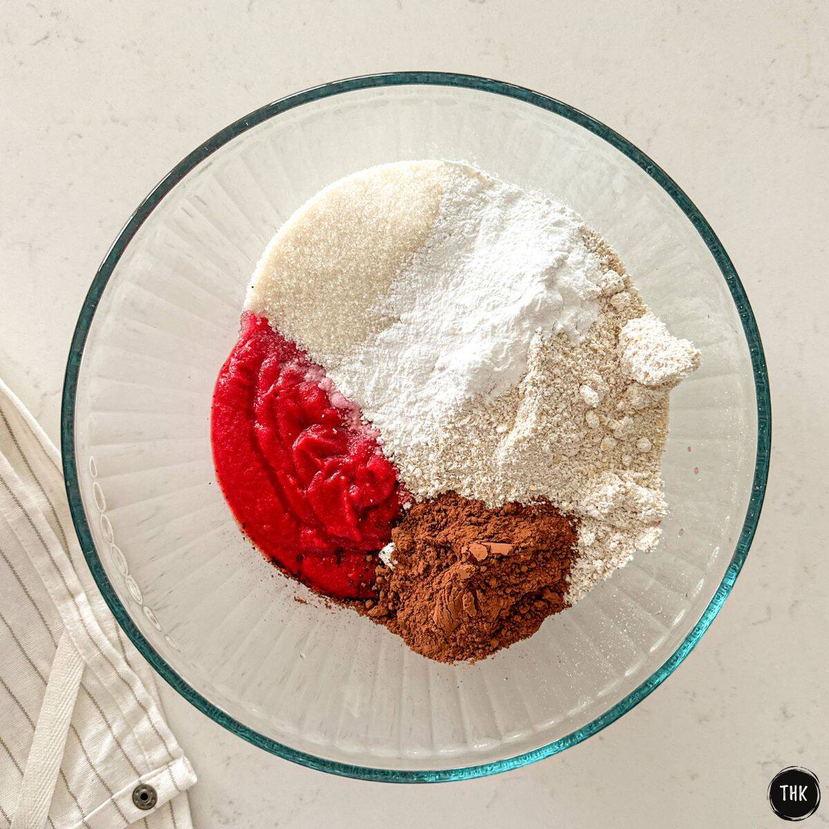 Large glass bowl with pureed beets, flour, sugar, cocoa powder and baking soda inside.