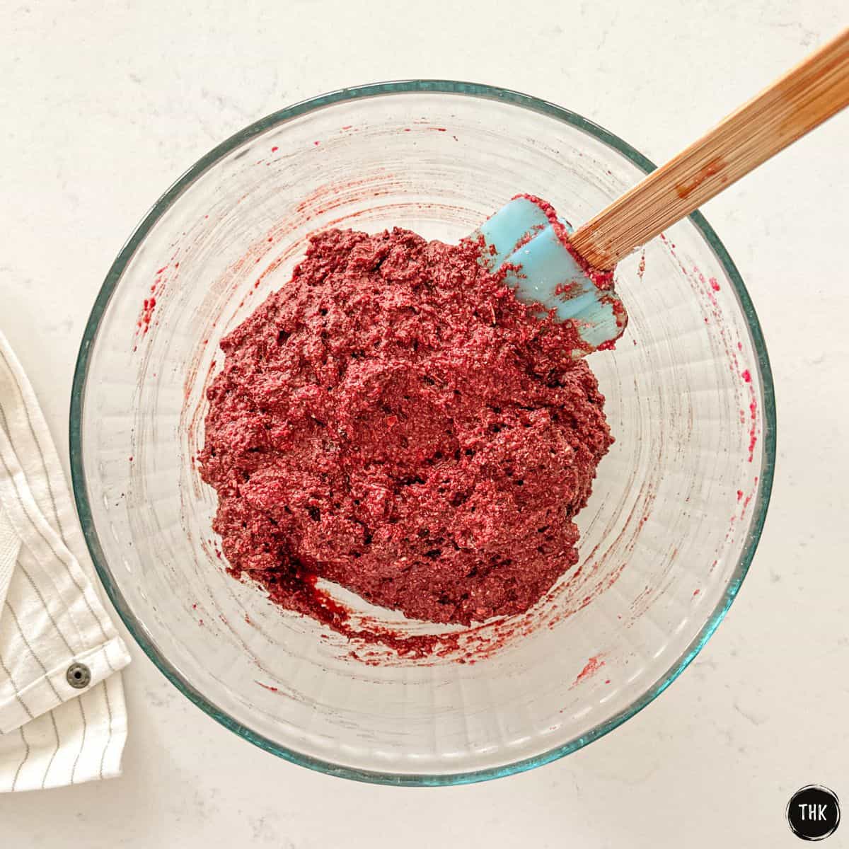 Vegan beet cookie batter inside large glass mixing bowl.