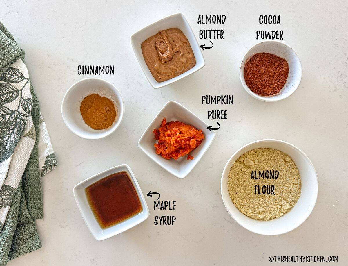 Ingredients to make pumpkin protein balls in prep bowls on countertop.