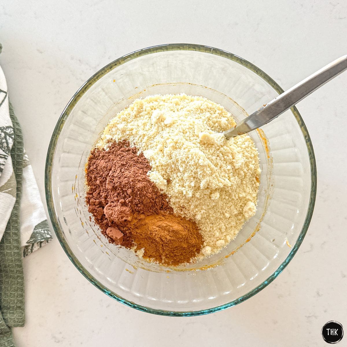 Glass bowl with almond flour, cocoa powder, and cinnamon.