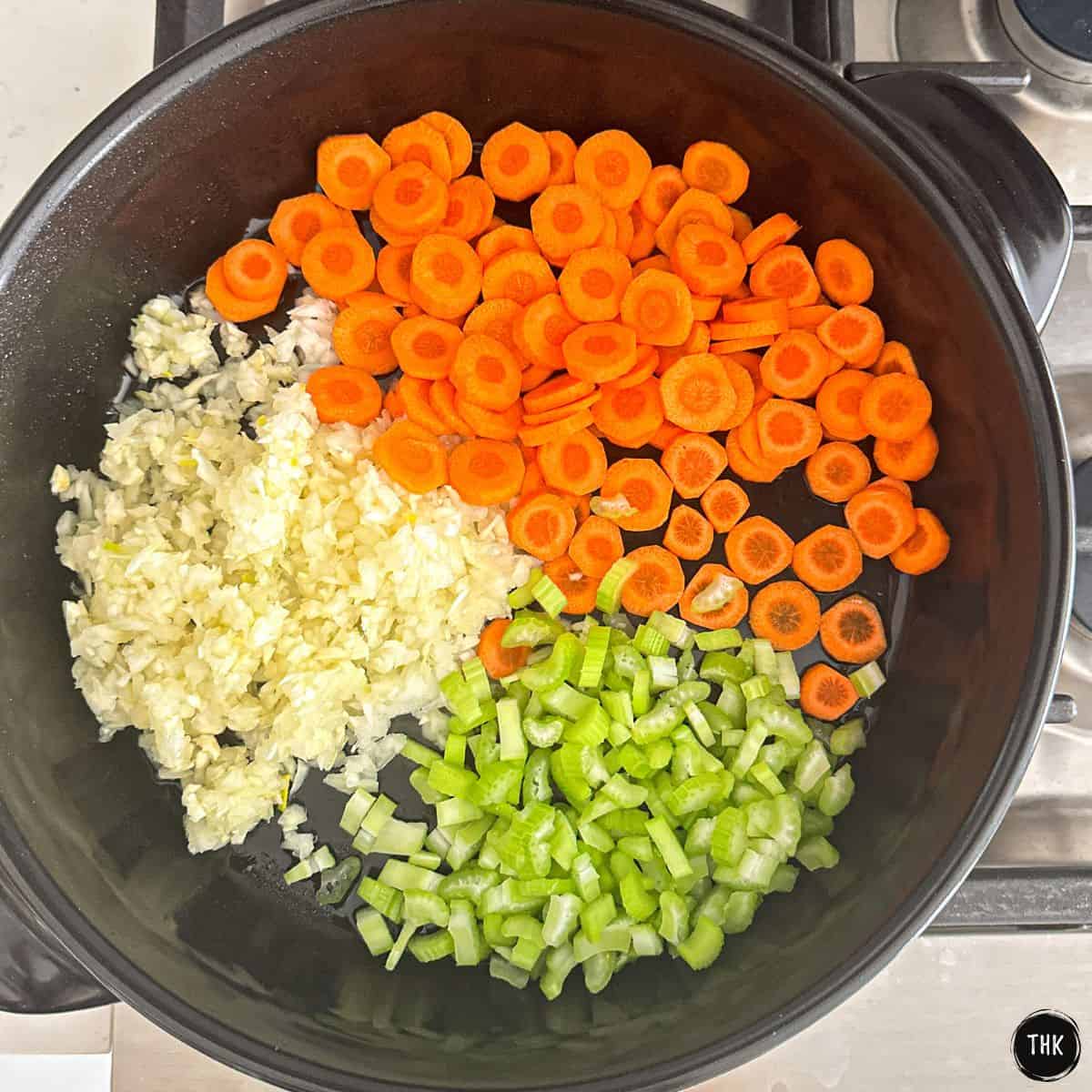 Ceramic skillet with sliced carrots, diced onion and sliced celery inside.