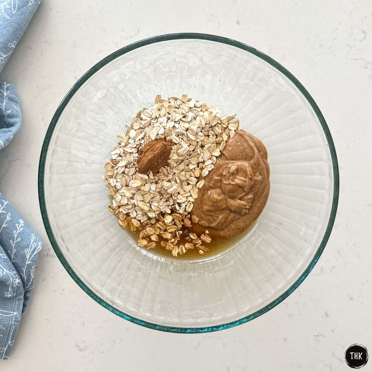 Glass bowl with oats, cinnamon, almond butter and maple syrup inside.